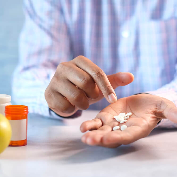 Un homme tient dans sa main les pilules d'une bouteille de médicaments